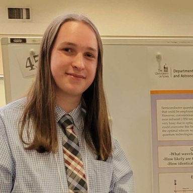 young person with shoulder length hair smiling slightly