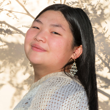 young asian woman with long dark hair, head tilted, smiling