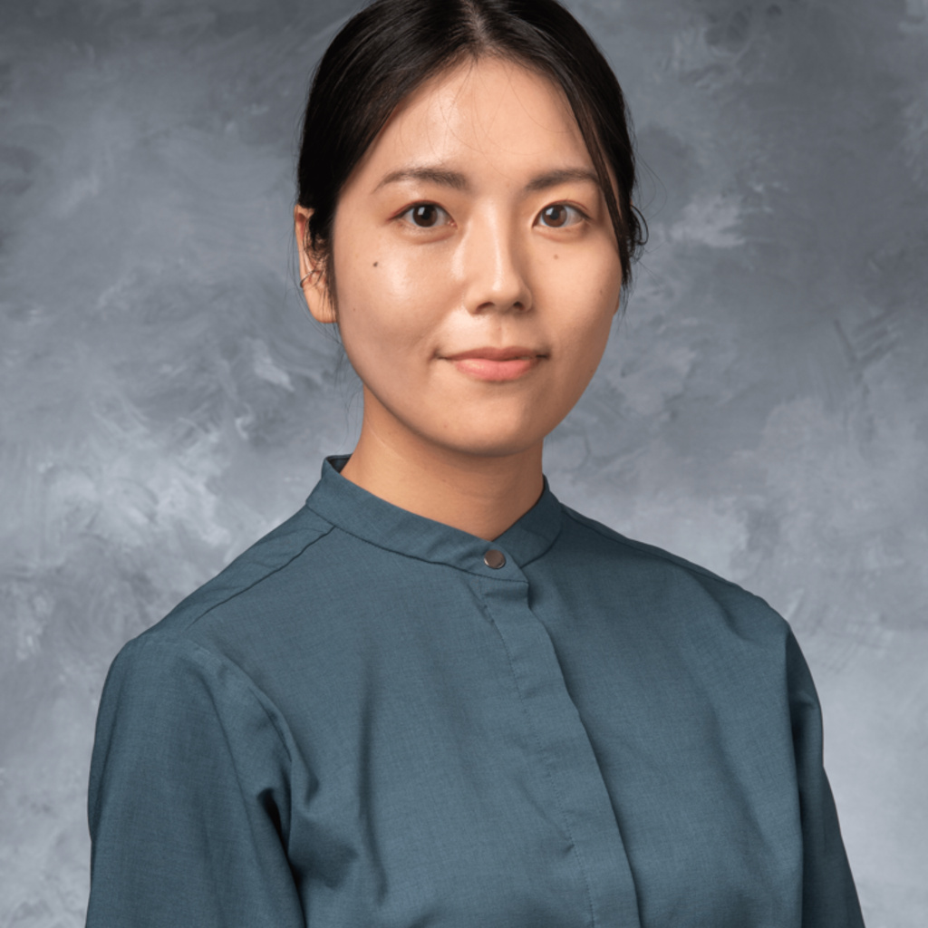 female presenting individual with dark hair pulled back and a gray shirt