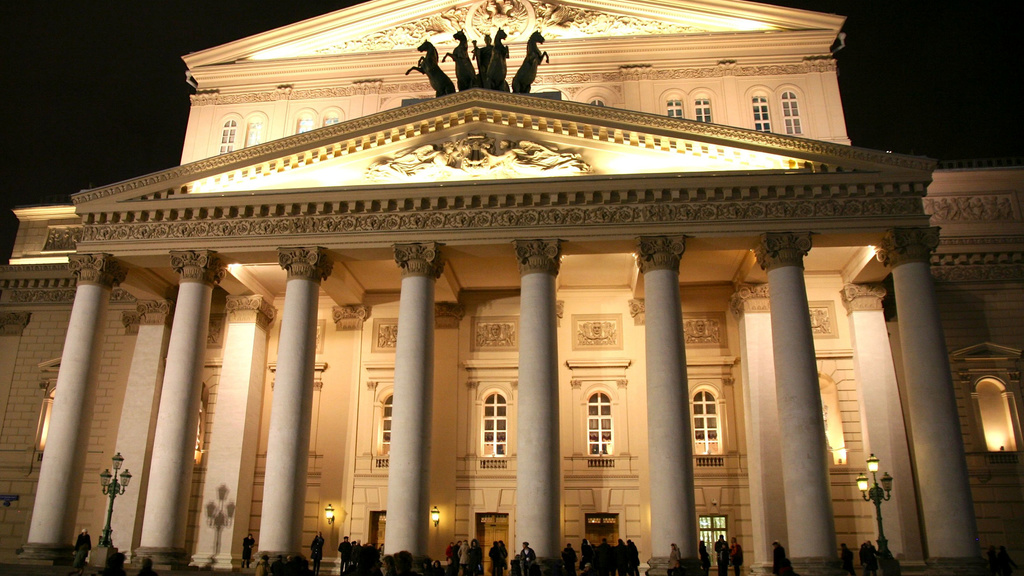 The Bolshoi (Grand) Theater glowing with lights in the night sky.