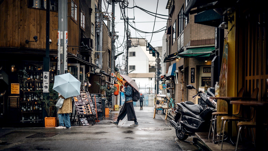 A person walking with an umbrella along a Tokyo street.