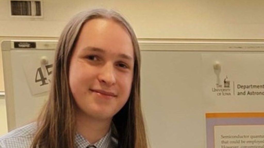 young person with shoulder length hair smiling slightly