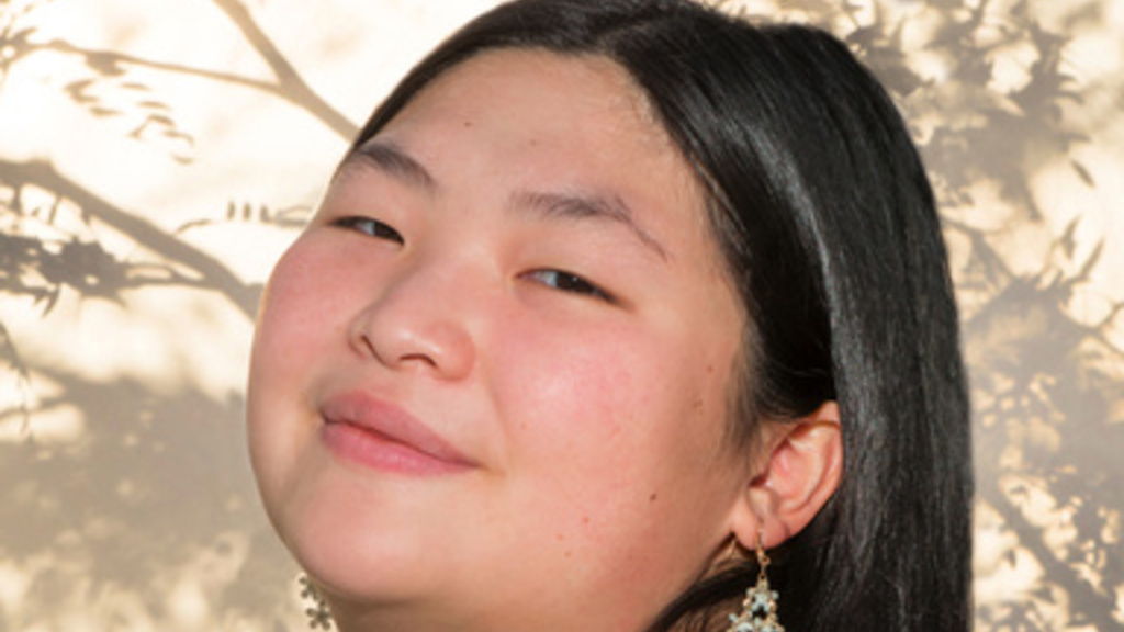 young asian woman with long dark hair, head tilted, smiling